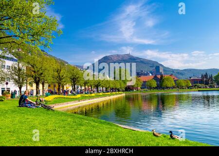 Menschen entspannen auf dem Rasen mit Fahrrädern von Lille Lungegårdsvannet im Frühling in Bergen, Norwegen Stockfoto