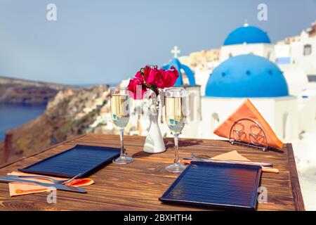 Zwei Gläser Weißwein auf dem Tisch, vor der Kulisse der Insel Santorini Stockfoto