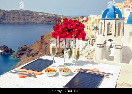 Zwei Gläser Weißwein auf dem Tisch, vor der Kulisse der Insel Santorini Stockfoto