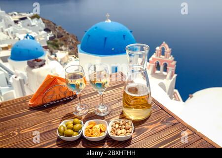 Eine Flasche Wein und zwei Gläser auf dem Tisch, vor der Kulisse der Insel Santorini Stockfoto