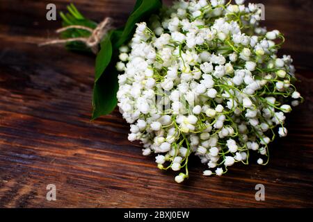 Zartes Bouquet der Maiglöckchen auf einem hölzernen Tisch. Blumenstrauß für den Urlaub. Selektiver Fokus. Stockfoto