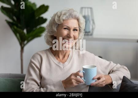 Portrait der lächelnden älteren Frau entspannen auf dem Sofa zu Hause Stockfoto