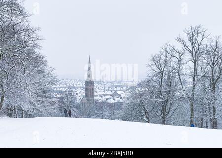Ein Paar, das im schweren Schneesturm in Glasgow durch den Queens Park in Glasgow läuft. Stockfoto