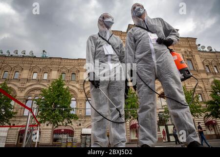 Moskau, Russland. 6. Juni 2020 Freiwillige, die Gesichtsmasken, Handschuhe und Schutzkleidung tragen, um sich vor dem Coronavirus zu schützen, versammeln sich, um einen Bereich eines Buchmarktes im Freien zu reinigen, der während der neuartigen Coronavirus-Epidemie in Russland auf dem Roten Platz in Moskau eingerichtet wurde. Moskauer mit Gesichtsmasken und Handschuhen wagten sich auf den Roten Platz für einen Buchmarkt im Freien. Stockfoto