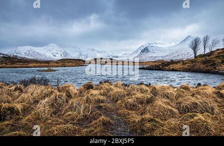 Winter schottische Highlands Landschaft mit stürmischem Himmel. Schneebedeckte Gipfel der Black Mount Range über die Lochans von Rannoch Moor. Stockfoto