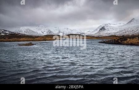Winter schottische Highlands Landschaft mit stürmischem Himmel. Schneebedeckte Gipfel der Black Mount Range über die Lochans von Rannoch Moor. Stockfoto