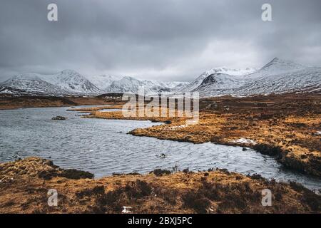 Winter schottische Highlands Landschaft mit stürmischem Himmel. Schneebedeckte Gipfel der Black Mount Range über die Lochans von Rannoch Moor. Stockfoto