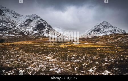 Malerische Winterlandschaft von Glen Coe mit den ikonischen "Three Sisters" und stürmischen Wolken am Horizont. Stockfoto