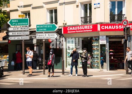 Menschen in Masken halten soziale Distanz, während sie darauf warten, am Straßenübergang in einem Pariser Vorort die Straße zu überqueren. Coronavirus-Sperre endet. Vincennes, Frankreich. Stockfoto