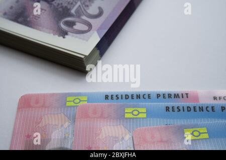 UK biometrische Aufenthaltstitel und 20 Pfund Banknoten. BRP-Karten für Tier 2 Arbeit Visum Einwanderer freigegeben. Konzept Bild für den Preis des Visums. Stockfoto