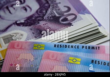 UK biometrische Aufenthaltstitel und 20 Pfund Banknoten. BRP-Karten für Tier 2 Arbeit Visum Einwanderer freigegeben. Konzept Bild für den Preis des Visums. Stockfoto