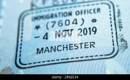 Einreisestempel im Reisepass, der von einem Einwanderungsbeamten an der Grenze und der Visumkontrolle am Flughafen Manchester in Großbritannien gemacht wurde. Selektiver Fokus. Makrofoto. Stockfoto