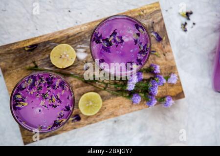 Frisches Lavendel Getränk mit Zitrone und Lavendelblüher. Kalter Sommer Violette Limonade, Ansicht von oben auf einem Holzbrett. Stockfoto