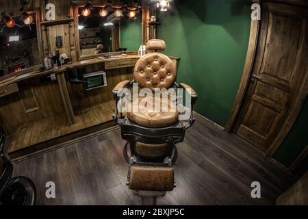 Vintage Barbershop Stuhl im Rampenlicht. Braun authentische Innenausstattung mit Holzelementen, geschmackvolles Design Stockfoto