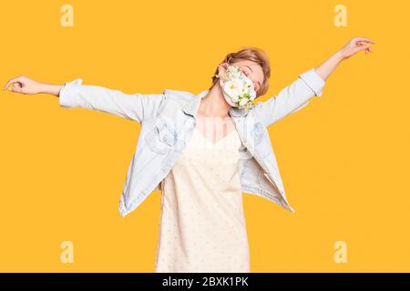 Schöne Frau in medizinische Maske mit Blumen-Design tanzen und Genießen Sie das Leben Stockfoto