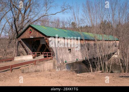 Hammond Covered Bridge in Pittsford, Vermont im Winter, dekoriert mit einem Weihnachtskranz. Stockfoto