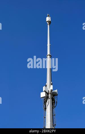 Ein Mast mit Telekommunikationsausrüstung auf einem Hintergrund des blauen Sommerhimmels. Kommunikation Türme auf blauen Himmel Hintergrund. Stockfoto