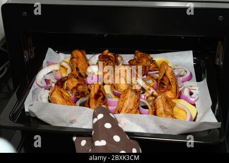 Hähnchenflügel mit Zwiebeln und Kartoffeln in einen Ofen stellen Stockfoto