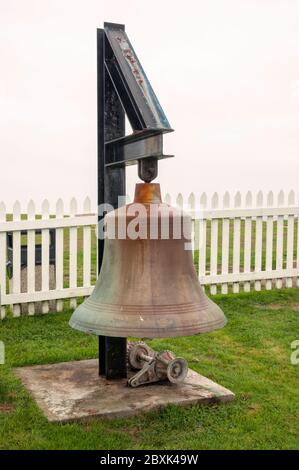 Eine große Glocke auf dem Gelände des Pemaquid Point Lighthouse, in Bristol, Lincoln County, Maine, mit einem weißen Zaun. Stockfoto