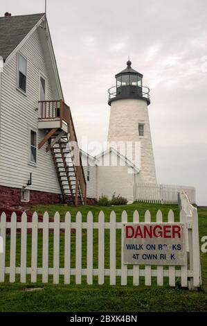 Ein nebliger Tag am Pemaquid Point Lighthouse, gelegen in Bristol, Lincoln County, Maine. Ein weißer Zaun umgibt den Leuchtturm und die Gebäude. Stockfoto