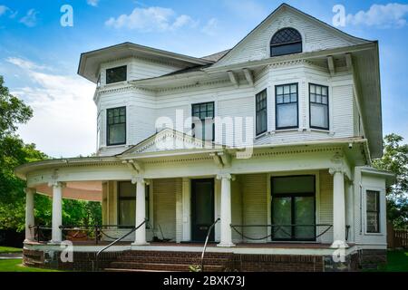 Ein alterndes Haus, in stilisiertem griechischen Revival mit Queen Ann Elementen gestaltet, mit seiner umlaufenden Veranda und Kettengliederrahmen Swag Geländer Akzente in St. Clou Stockfoto