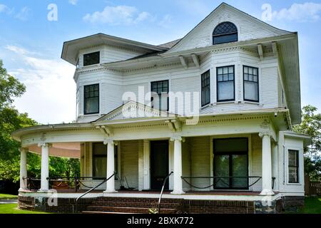 Ein alterndes Haus, in stilisiertem griechischen Revival mit Queen Ann Elementen gestaltet, mit seiner umlaufenden Veranda und Kettengliederrahmen Swag Geländer Akzente in St. Clou Stockfoto