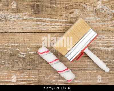 Eine Malrolle und ein großer Pinsel auf einem Holzhintergrund. Stockfoto