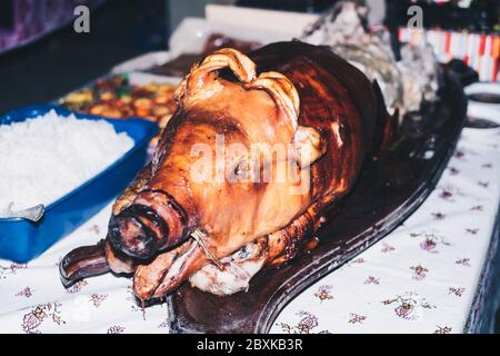 Nahaufnahme der halbfrontalen Ansicht des beliebten gerösteten Schweins auf dem Tisch, bekannt als "Lechon" auf den Philippinen, Spanien, Kuba, etc. Selektiver Fokus. Stockfoto