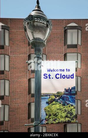 Retro antike Straßenlampenpost, mit einem Banner aufgehängt, mit der Aufschrift "Welcome to St. Cloud" mit Foto des Mississippi River Waterfront in St. Cloud, MN, USA Stockfoto