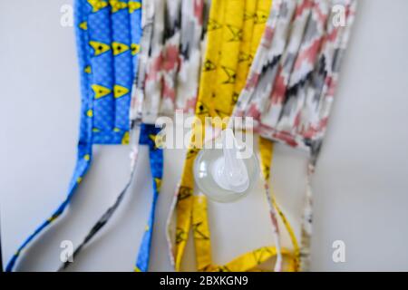 Wiederverwendbare Stofffakemasken mit einer Flasche Desinfektionsmittel zur Verwendung während der Covid 19 Coronavirus Pandemie Stockfoto