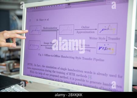 Erlangen, Deutschland. Juni 2020. Eine wissenschaftliche Mitarbeiterin am Lehrstuhl für Mustererkennung an der Universität Erlangen-Nürnberg erläutert die Schritte der Handschriftimitate durch Software anhand einer Grafik. Erlangen-Forscher imitieren mit künstlicher Intelligenz die Handschrift. Ein Ziel ist es, Menschen zu ermöglichen, die aufgrund von Verletzungen oder anderen Beeinträchtigungen keine Texte in eigener Handschrift schreiben können. Quelle: Daniel Karmann/dpa/Alamy Live News Stockfoto