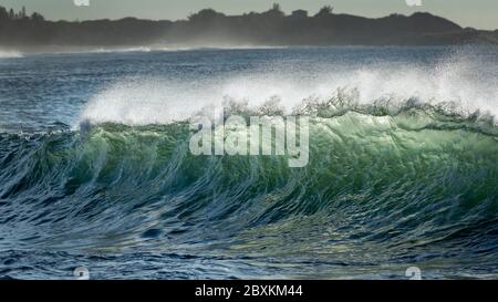 Sonnenlicht durch Wellen am Strand in Molokai, Hawaii sie Farben von grün und gold glänzend Stockfoto