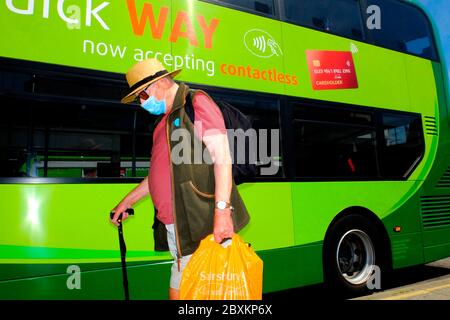Rentner älterer Mann trägt covid19 Maske Gesichtsbedeckung im Bus Haltestelle mit dem Bus in Busbahnhof kontaktlose Zahlung grün Go Ahead Group Southern Vectis Stockfoto