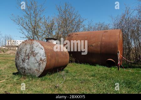 Zwei alte verlassene rostige Fässer liegen im Freien auf dem Gras. Stockfoto