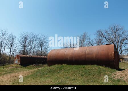 Zwei alte verlassene rostige Fässer liegen im Freien auf dem Gras. Stockfoto