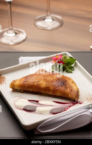 Süße Erdbeere und Sahne Krepp auf einem weißen Teller und Ledermatte und Holztisch Stockfoto