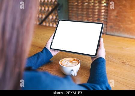 Mockup Bild von einer Frau mit schwarzen Tablet-PC mit leeren weißen Bildschirm mit Kaffee Tasse auf hölzernen Tisch Stockfoto