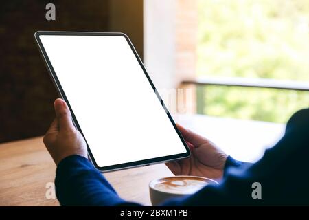 Mockup Bild von einer Frau mit schwarzen Tablet-PC mit leeren weißen Bildschirm mit Kaffee Tasse auf hölzernen Tisch Stockfoto