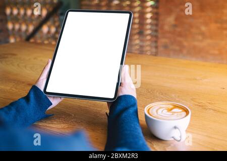 Mockup Bild von einer Frau mit schwarzen Tablet-PC mit leeren weißen Bildschirm mit Kaffee Tasse auf hölzernen Tisch Stockfoto