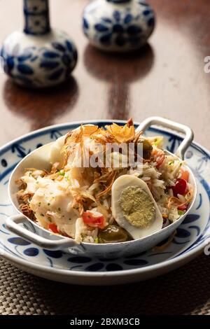 Kabeljau Fisch Bacalhau mit Reis, Zwiebeln Eier Olivenöl - portugiesisch traditionelle Lebensmittel auf Holztischunterlage und verschwommener Hintergrund Stockfoto