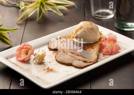 Crepe mit Karamell Dulce de leche Füllung und Vanilleeis auf Holztisch Stockfoto