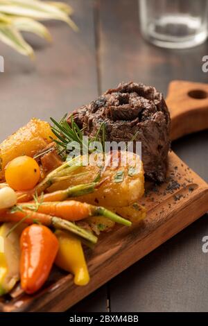 Flanke flaches Eisen Rock Steak mit Gemüse auf einem Holzbrett und verschwommener Hintergrund Stockfoto