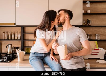 Küssen junge Paar hat eine gute Zeit zusammen zu Hause beim Essen chinesisches Essen Stockfoto