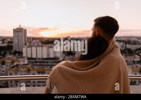 Nahaufnahme Porträt, Mann und Frau lächeln einander bei Sonnenuntergang mit Stadt im Hintergrund. Romantische Momente im intimen Kreis Stockfoto