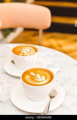 Cappuccino auf dem weißen Marmortisch in einem modernen Café. Auszeit, Kaffee, Luxus, Freunde Meeting Konzept. Platz für Text Stockfoto