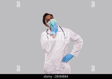 Indischer Mann Doktor Denkzeichen Tragen medizinische Maske und Handschuhe. Arzt Wacht Auf. Isoliert Stockfoto
