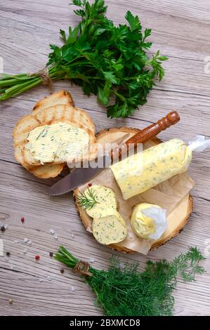 Butter mit einem Kraut für Sandwiches und Steak. Teil der Kräuterbutter auf einem Holzbrett geschnitten. Hausgemachte italienische Küche. Stockfoto