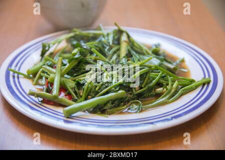 'Pad Pak Boong' ein traditionelles thailändisches Gericht: Gebratenes 'Morning Glory'-Gemüse (Ipomoea aquatica), auf der Pfanne gegrillt Stockfoto