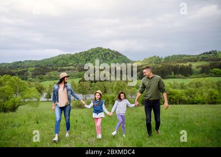 Glückliche Familie mit zwei kleinen Töchtern, die im Frühling in der Natur unterwegs sind. Stockfoto