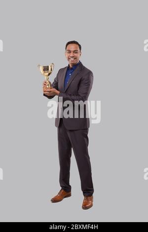 Trophy Für Geschäftsleute. Indische Geschäftsmann stehend voller Länge mit Trophäe in den Händen Stockfoto
